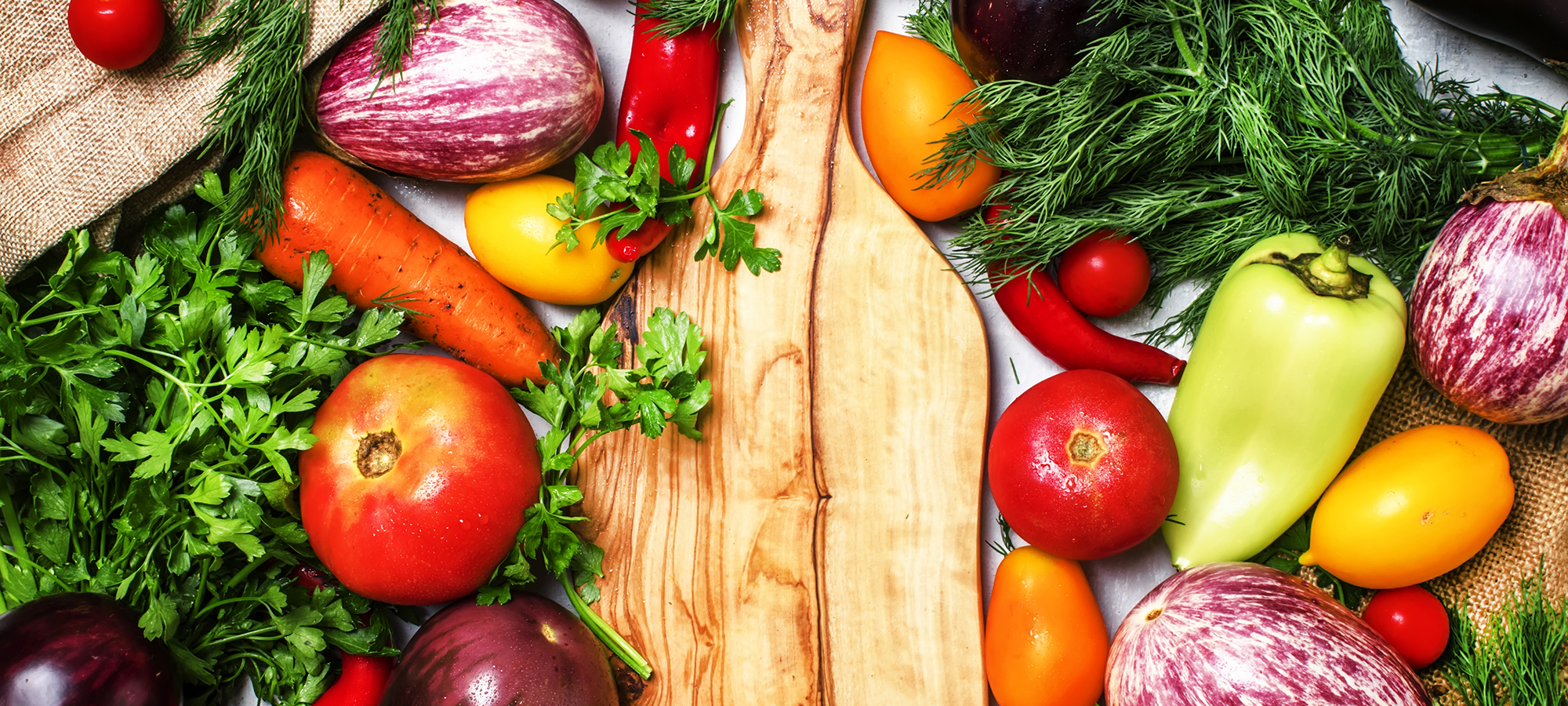 Cooking background, fresh vegetables and spicy herbs on a cutting board, top view