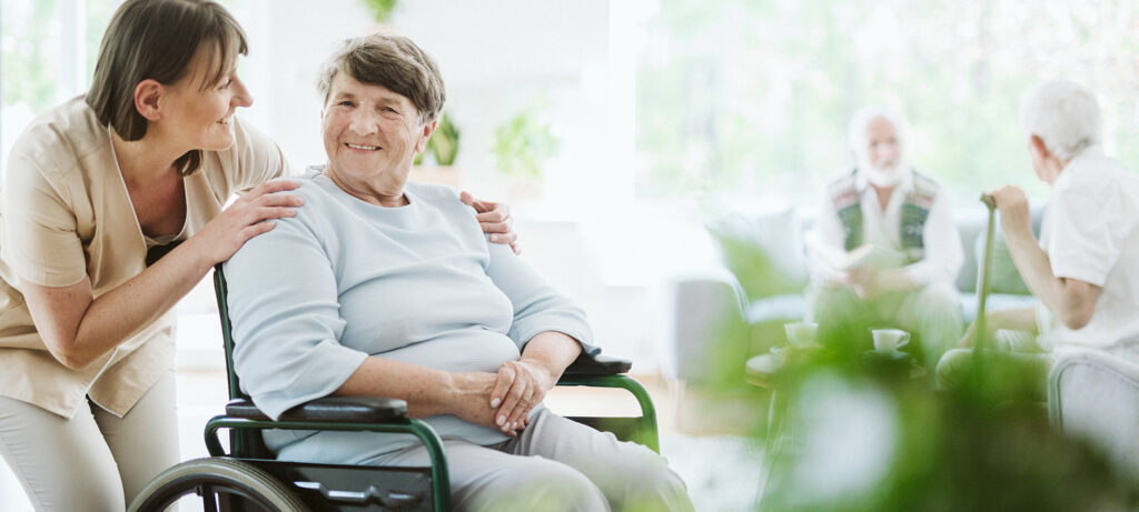 Happy caregiver with elder patient on the wheelchair